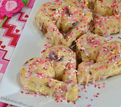 heart shaped cinnamon rolls with pink, white, and red sprinkles